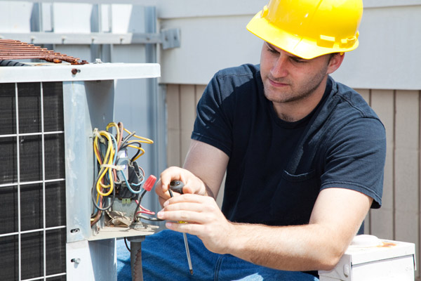 image of an HVAC contractor performing annual air conditioner maintenance