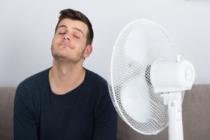 man sitting in front of fan due to high humidity