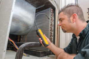 HVAC technician looking at AC evaporator coil