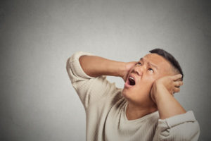 man covering ears from noisy air conditioning system