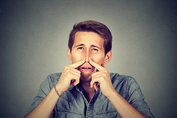 image of person plugging nose due to dead animal in hvac air duct