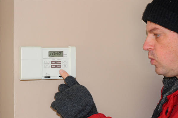 image of a homeowner cranking up the thermostat