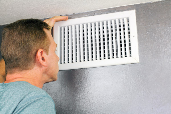 homeowner inspecting HVAC air vent