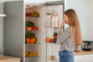 image of homeowner plugging nose due to rotten food in fridge