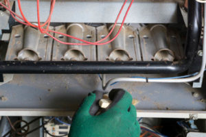 HVAC Technician Cleaning A Leaking Natural Gas Furnace