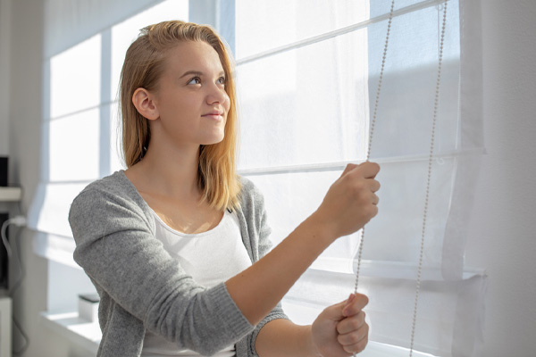 homeowner closing curtain to block the sun