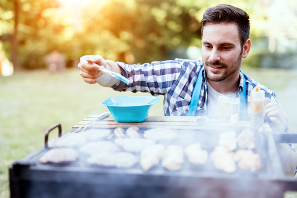 image of a homeowner grilling outside to prevent heat inside home