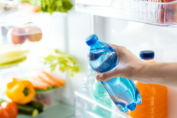 image of homeowner taking cold water bottle out of fridge depicting keeping cool naturally