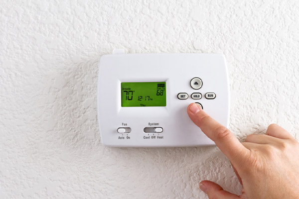 https://www.lawescompany.com/wp-content/uploads/2022/06/image-of-homeowner-adjusting-heat-pump-thermostat-since-heat-pump-compressor-not-turning-on.jpg