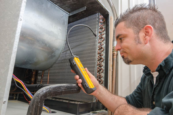 hvac technician with an air conditioner refrigerant leak detector