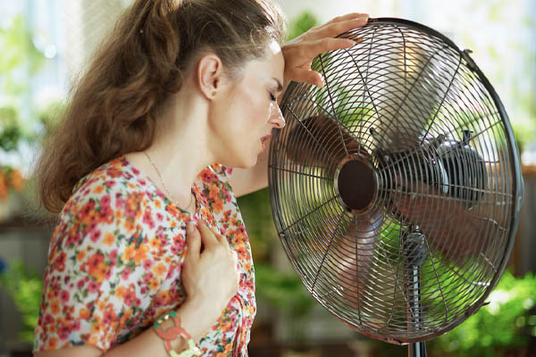 image of homeowner feeling hot due to an air conditioning system that blows warm air
