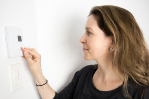 image of a woman adjusting thermostat depicting furnace wont turn on with thermostat