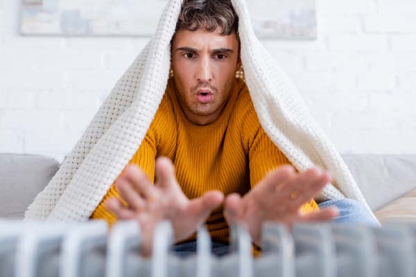 image of a homeowner in front of space heater depicting furnace blowing cold air