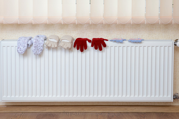 image of knitted gloves on radiator of an oil-fired home heating system