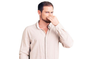 man plugging nose due to furnace burning odor
