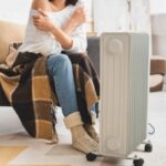 woman with blanket trying to keep warm with an electric space heater due to furnace malfunction