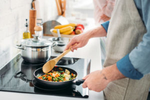 image of a homeowner cooking and using mechanical ventilation to prevent odors