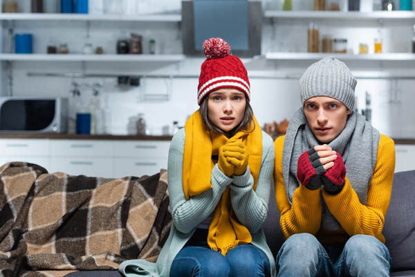 image of a homeowner feeling chilly due to poor heating pump performance in winter