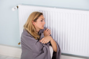 image of a homeowner sitting by radiator and boiler not producing heat