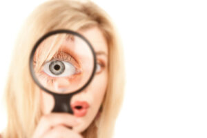 close up of a woman looking through a magnifying glass depicting top signs of poor indoor air quality