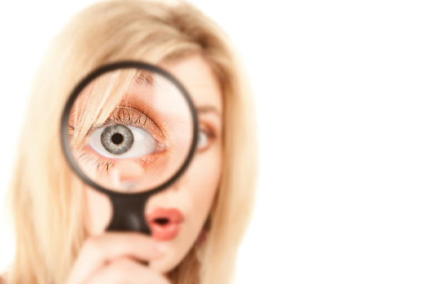 close up of a woman looking through a magnifying glass depicting top signs of poor indoor air quality