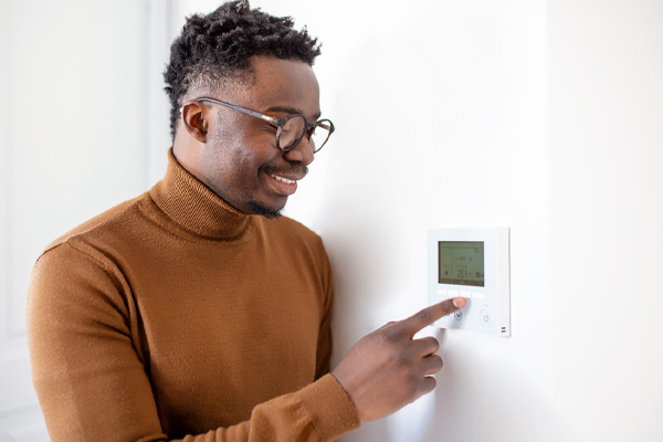 image of a homeowner turning off thermostat due to frozen ac unit