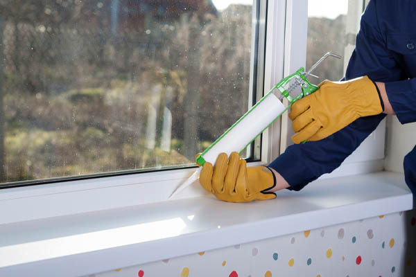 image of homeowner using silicone to seal window