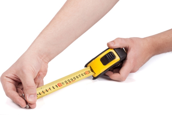 man holding a tape measure depicting furnace size