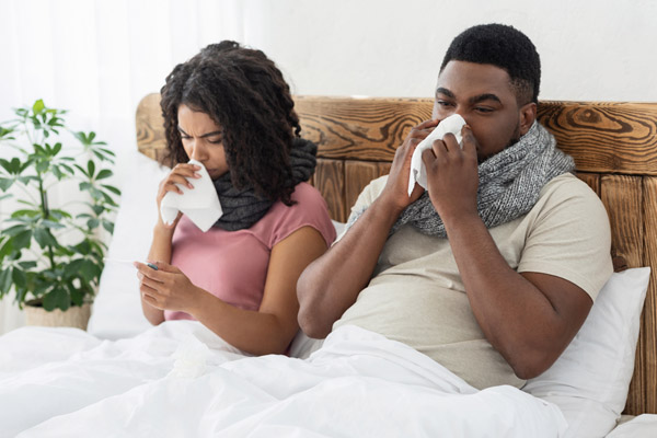 sick couple in bed depicting poor iaq