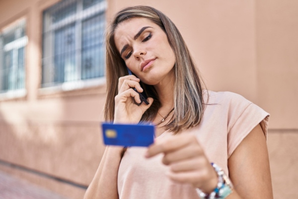 Woman on a phone call holding credit card depicting analysis of home HVAC upgrade