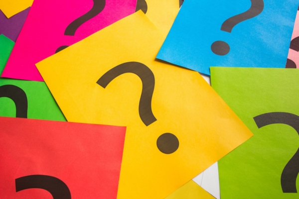 Black question marks on the colored papers depicting How to Hide a Generator with Landscaping FAQs