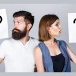 Portrait of couple holding paper question mark depicting repair or replace air conditioner