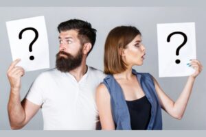 Portrait of couple holding paper question mark depicting repair or replace air conditioner