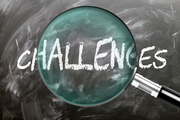 magnifying glass enhancing the word challenges on a chalkboard depicting air conditioner replacement