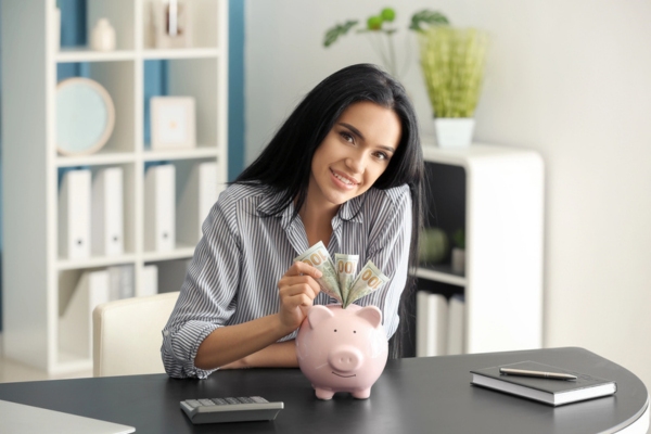 woman putting dollar bills in a piggy bank depicting long term savings