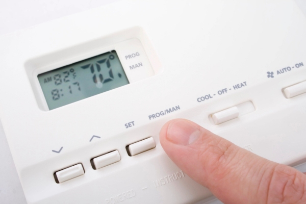 homeowner adjusting HVAC thermostat