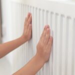 Child warming hands on heating radiator indoors