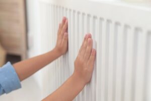 Child warming hands on heating radiator indoors