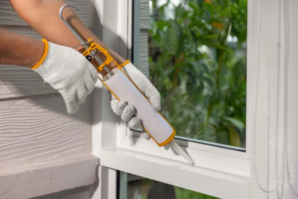 man sealing window to avoid air leak