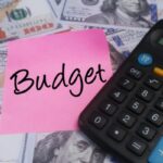 budget written on a sticky note with dollar bills and calculator around