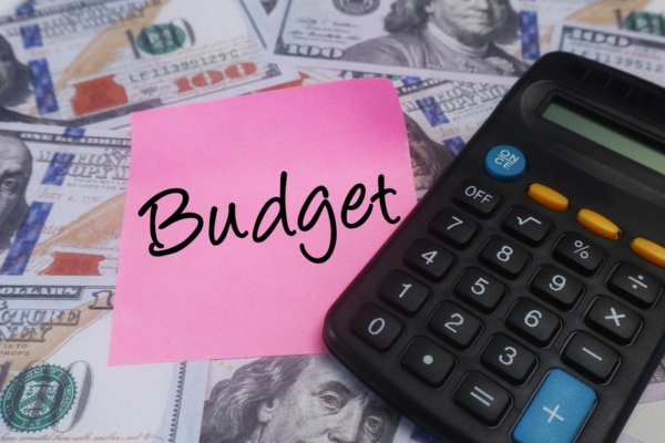 budget written on a sticky note with dollar bills and calculator around