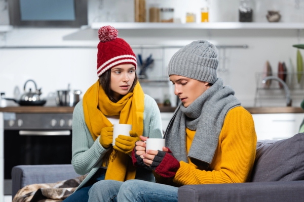 couple feeling cold indoor in full winter gear due to running low on heating oil