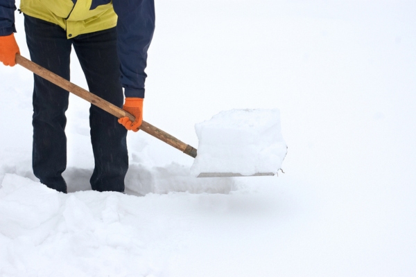 homeowner manually clearing snow to create path at home