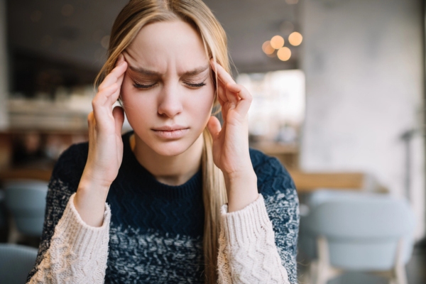 young woman experiencing headache indoors depicting Carbon Monoxide Accumulation Hazards
