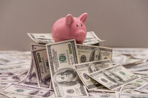 piggy bank on top of dollar bank notes depicting saving money