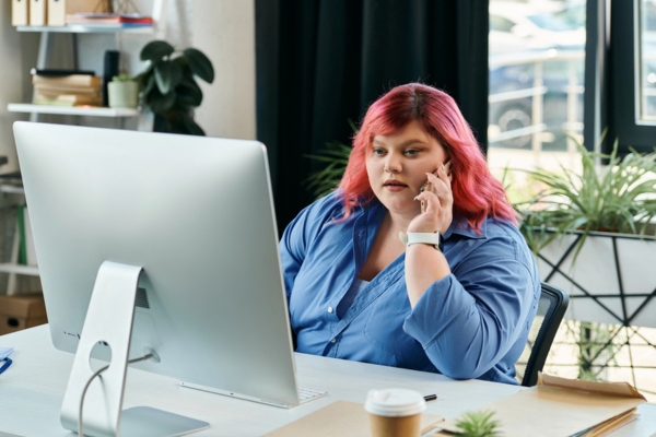 woman with red hair at the office talking on the phone with a customer