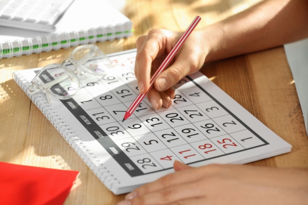 cropped view of a woman's hand marking a date in a calendar for HVAC repair schedule