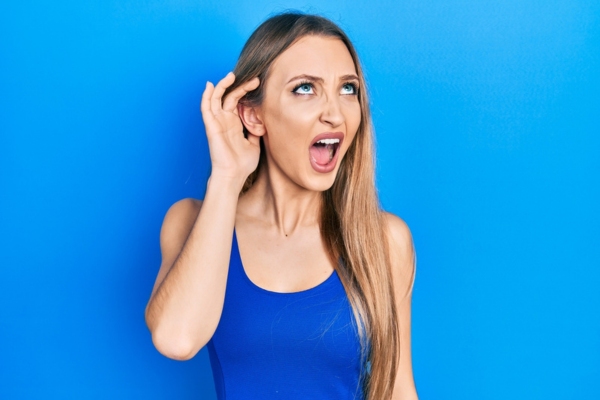 woman looking up while cupping right ear depicting strange HVAC sounds