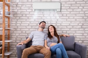 Couple Sitting Under Air Conditioner On Couch