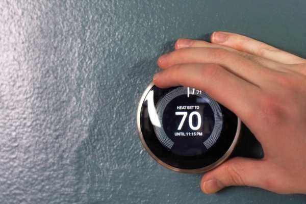 homeowner adjusting home thermostat to prepare for warmer weather